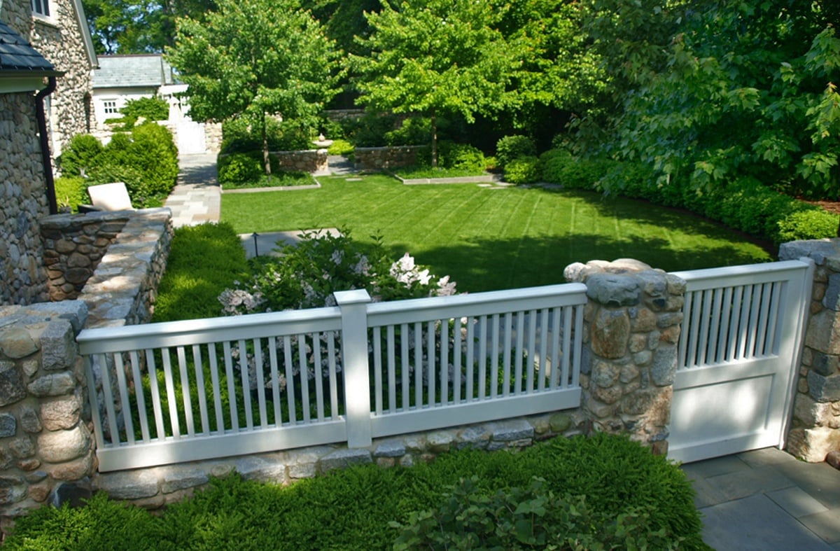 white picket fence in backyard with cobblestone pillars